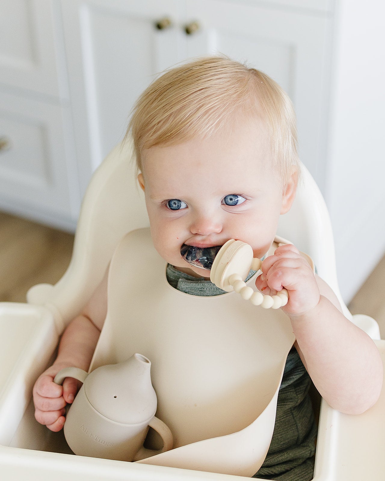 baby using pacifier fruit feeder and wearing a silicon bib