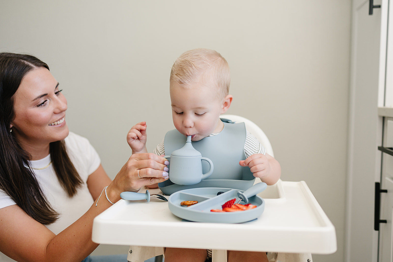 Baby using a silicon bib, silicon food grade plate with sections and soft silicone sippy cup for babies