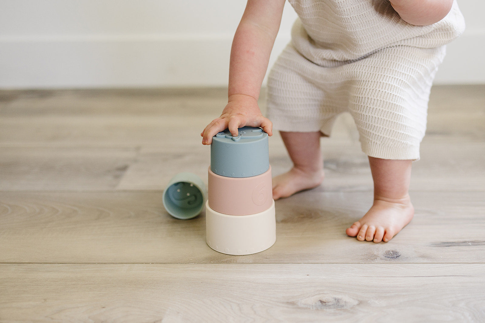 Child playing with colorful stacking toys on a wooden floor