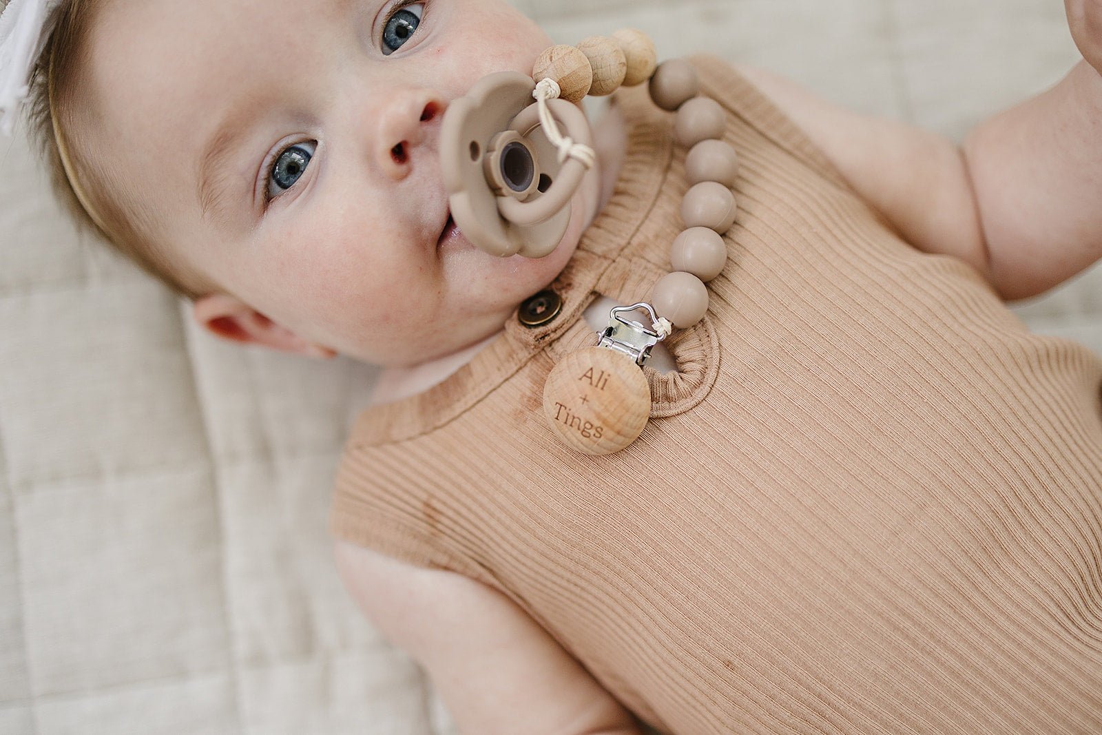 Ali + Tings pacifier clip attached to baby outfit